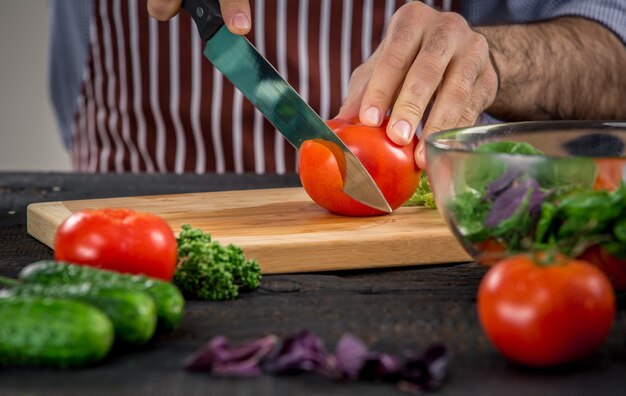 Male hands cutting vegetables for salad