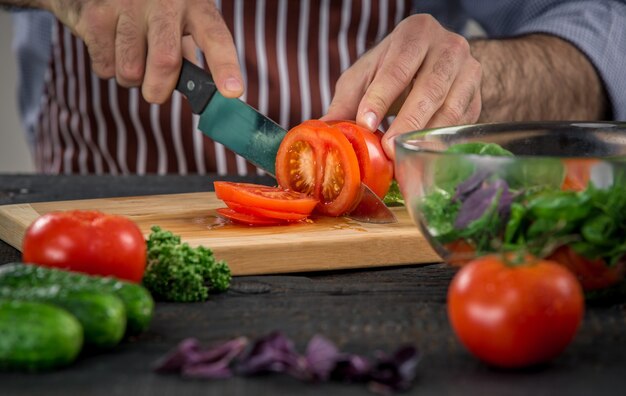 Photo male hands cutting vegetables for salad