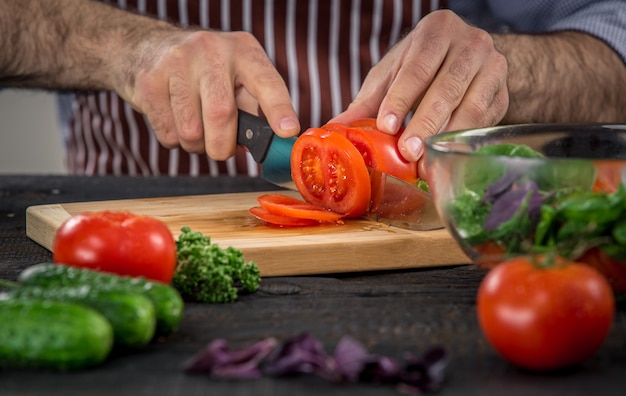 Male hands cutting vegetables for salad