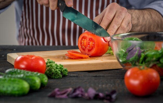 Male hands cutting vegetables for salad