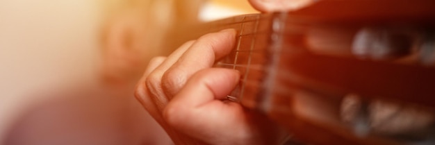 Male hands elderly senior caucasian man holding and playing classical guitar close up at home unprofessional faceless guitarist people play amateur music domestic hobbies and leisure banner flare