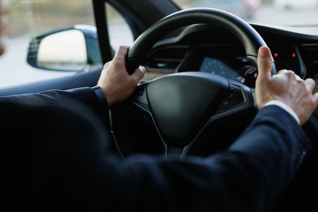 Male hands hold the steering wheel of a car view from the inside of the cabin safety and attention