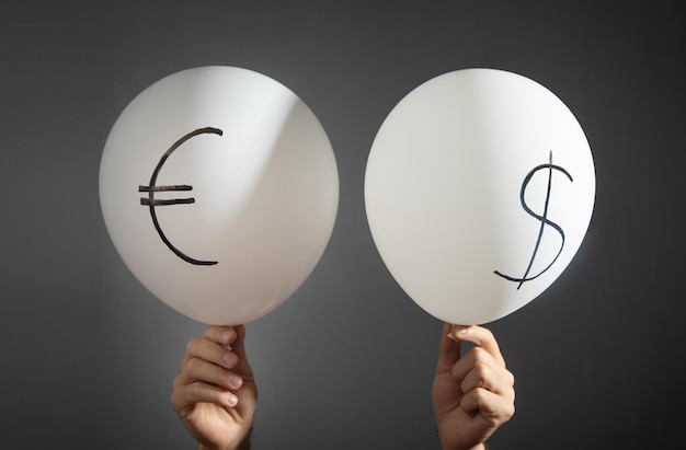 Male hands holding dollar and euro symbols on balloons