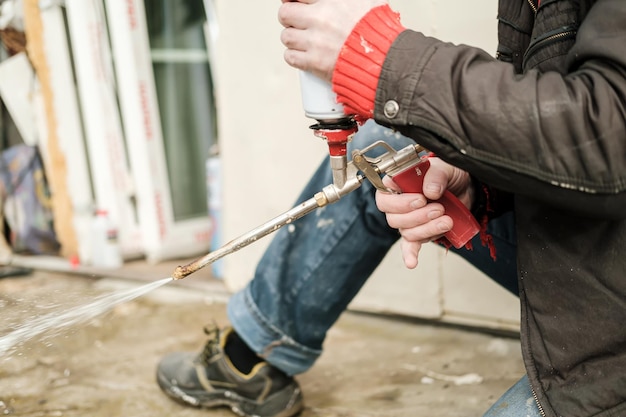 Male hands holding old professional gun for aerosol insulating foam with a balloon and checking it