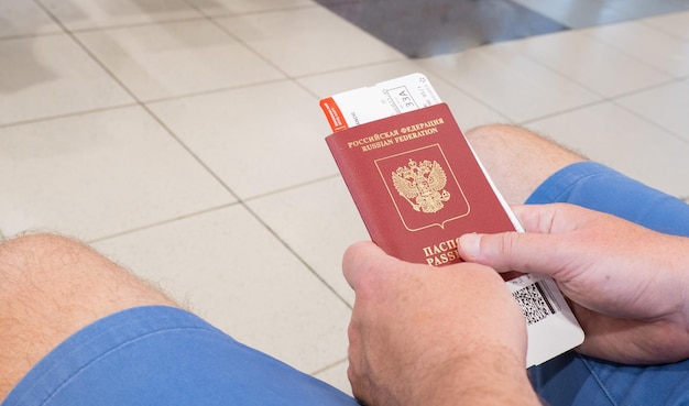 Male hands holding passport with plane tickets top view