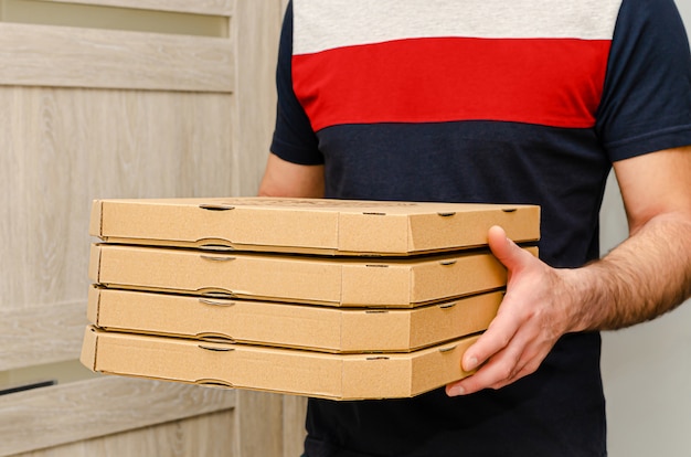 Male hands holding pizza cardboard boxes. Food order and delivery.