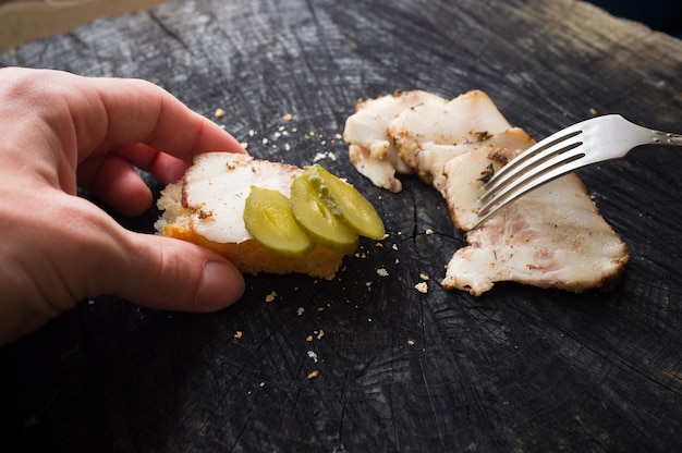 Male hands holding salo pickled cucumber pinning piece by fork