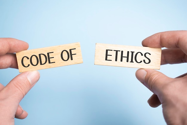 Male hands holding two wooden pegs with Code of Ethics