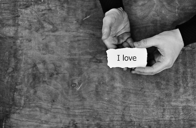 Photo male hands holding a white blank sheet of paper on the background of wooden texture table