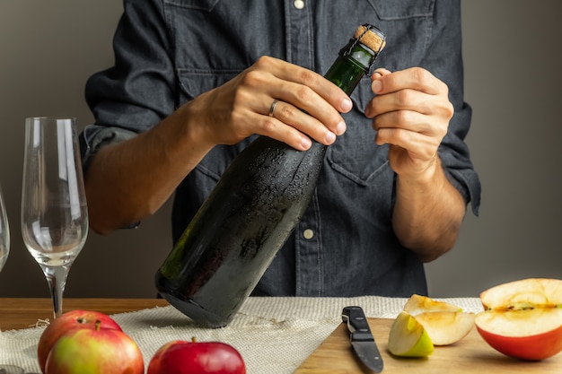 Male hands opening bottle of premium cidre. Uncorking beautiful ice cold bottle of apple wine