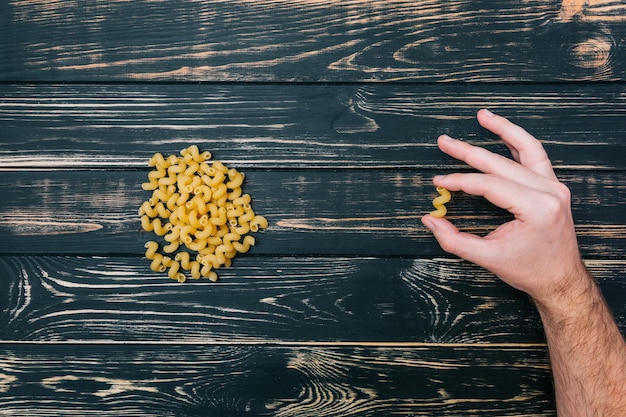 In male hands pasta on black wooden background