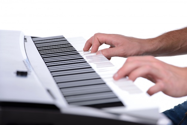 Male hands playing digital piano on white.