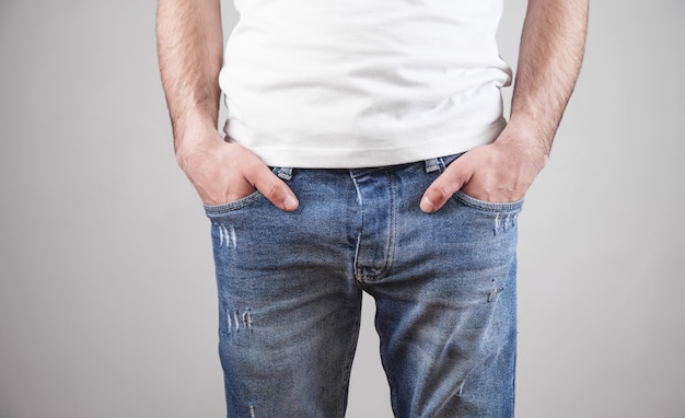 Male hands in pocket of jeans on grey