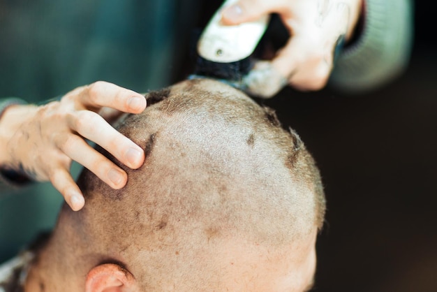 Male hands shaving head of a customer