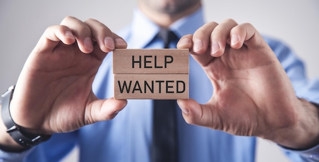 Male hands showing Help Wanted text on wooden blocks