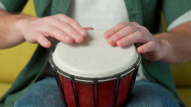 Male hands tapping djembe, bongo in rhythm.