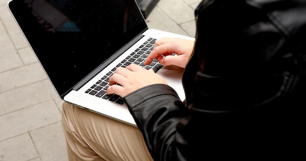 Male hands typing on laptop keyboard outdoor business and technology concept.