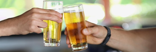 Male hands with glasses of beer clink glasses