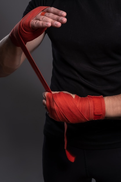 Male hands wrapped with red boxing tape before fight