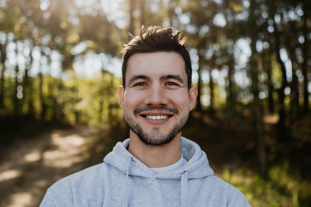 Male happy face portrait of young smiling attractive man posing outdoors looking at camera in woods