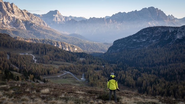 Male hiker with camera enjoying views on beautiful mountain valley during sunrise dolomites italy