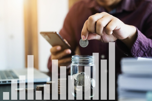 Male holding coins putting in glass with using smartphone to calculate concept saving money for finance accounting