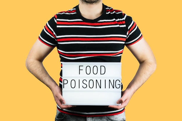 Male holding a paper with the writing "food poisoning" in front of his belly