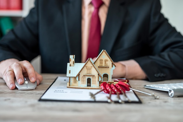 male house salesman checks the documents for a house sale contract before letting the customer sign the contract on the table this is a key to the house model concepts of real estate trading