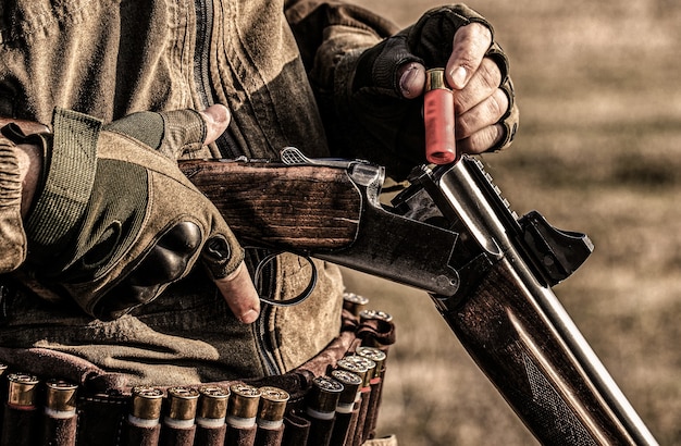 Male hunter in ready to hunt. Closeup. Hunter man. Hunting period. Male with a gun, rifle.