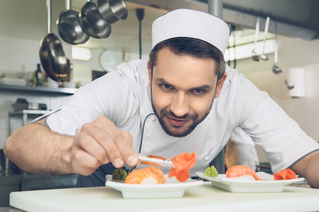 Male japanese restaurant chef cooking in the kitchen adding ingredients