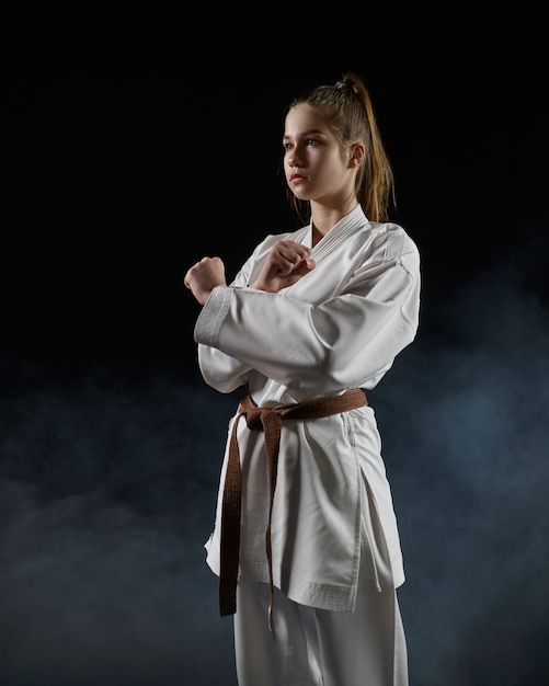 Male karate fighter in white kimono, welcome sign. Karateka on workout, martial arts, training before fighting competition