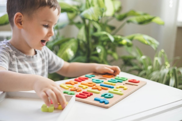 Male kid playing with wooden eco friendly alphabet letters board on table top view Intellectual game preschool primary education early development font characters for learning reading and writing