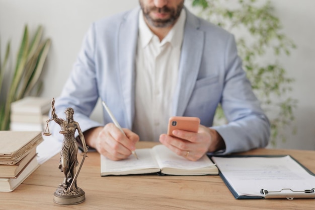 Male lawyer in a white shirt and jacket works in the office a statuette of the goddess of justice