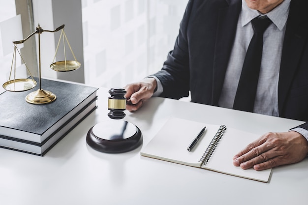 Male lawyer with papers, Law books, wooden gavel and scale on a table.