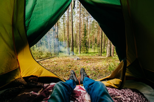 Male legs lying in camping tent with a view at forest