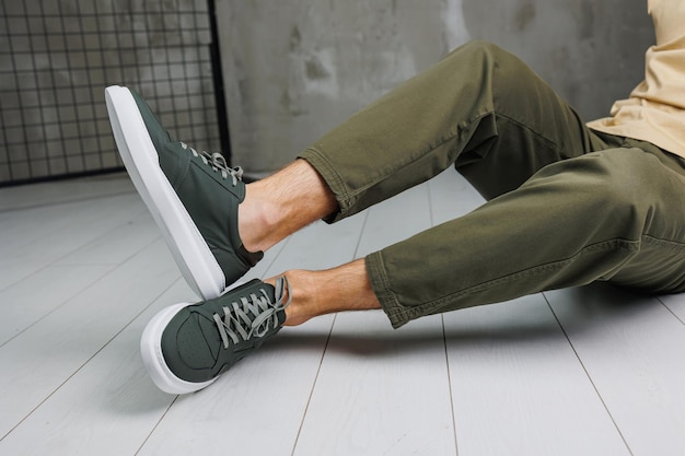 Male legs in pants and green casual sneakers Men's fashionable shoes