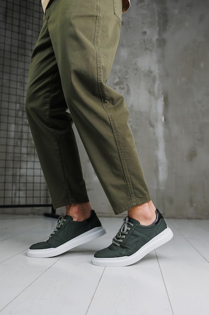 Male legs in pants and green casual sneakers Men's fashionable shoes