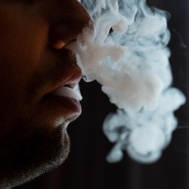 Male lips blowing smoke closeup cigarette smoke and lips on black background