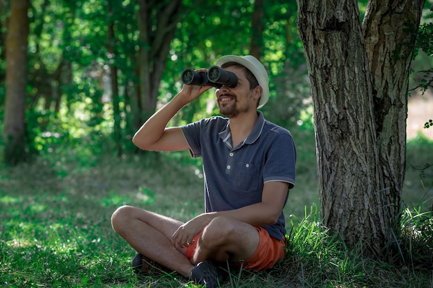 Male looking through binoculars in forest