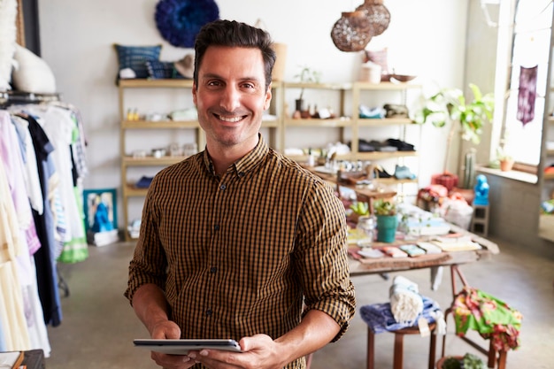 Photo male manager with tablet computer standing in clothes shop