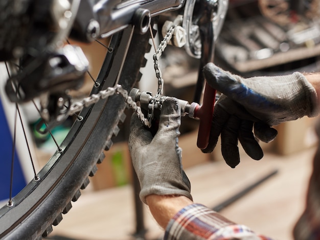 Male mechanic making service in bicycle repair shop using tools