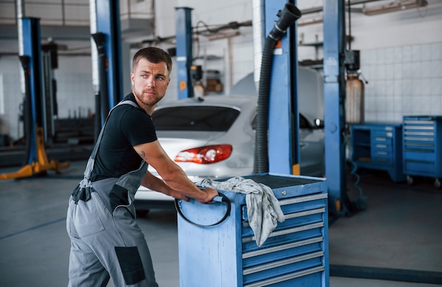 Male mechanic use different tools to repair broken automobile in garage