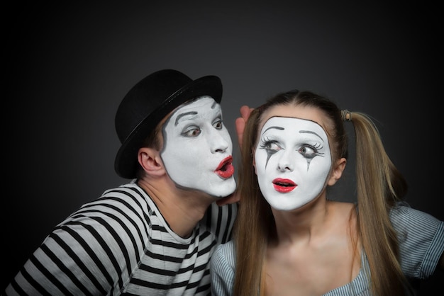 Male mime sharing secret with surprised female mime