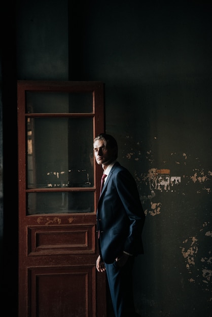 Male model in black suit and red tie poses for men's clothing advertising. Shooting for men's clothing store