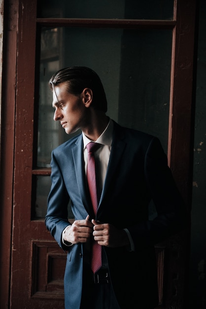 Male model in black suit and red tie poses for men's clothing advertising. Shooting for men's clothing store