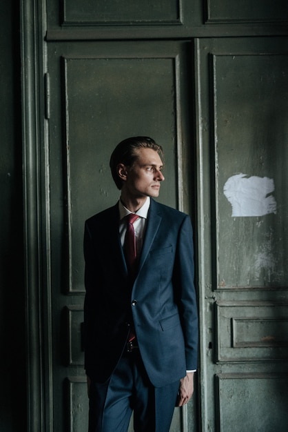 Male model in black suit and red tie poses for men's clothing advertising. Shooting for men's clothing store