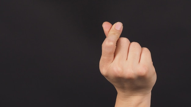 Male model is doing mini heart hand sign on black background.