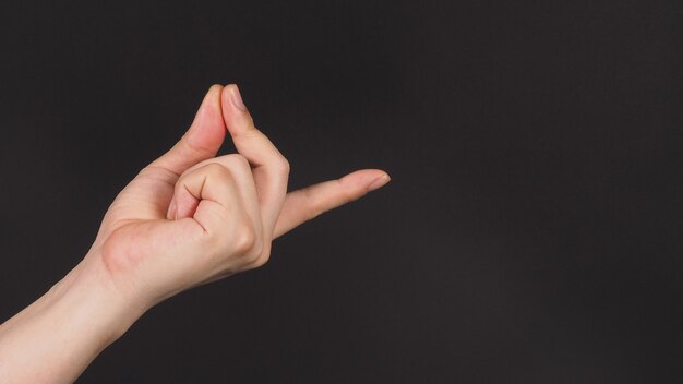 Photo male model is doing snap gesture with left hand sign on black background.