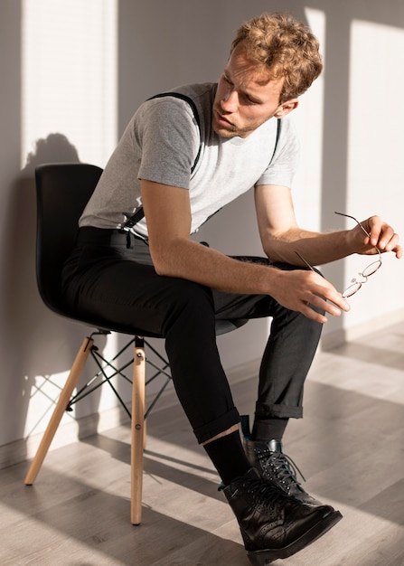 Male model with curly hair sitting on a chair and looking away