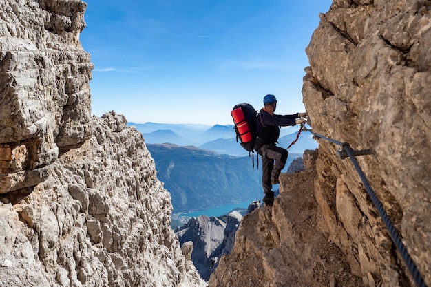 Male mountain climber on a Via Ferrata in breathtaking landscape of Dolomites Mountains in Italy Travel adventure concept